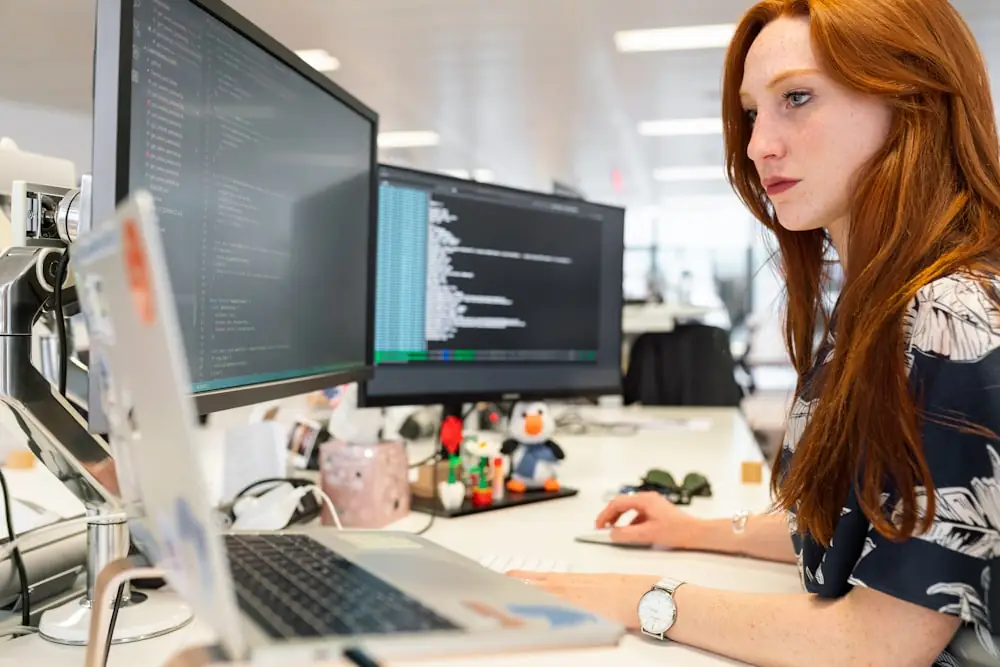 An analyst working at a screen of code in a bright office