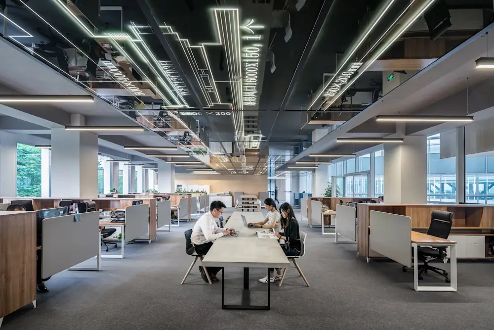 An open-plan office with people working at a long shared desk