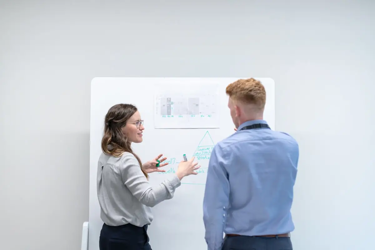 Two colleagues working through an idea at a whiteboard