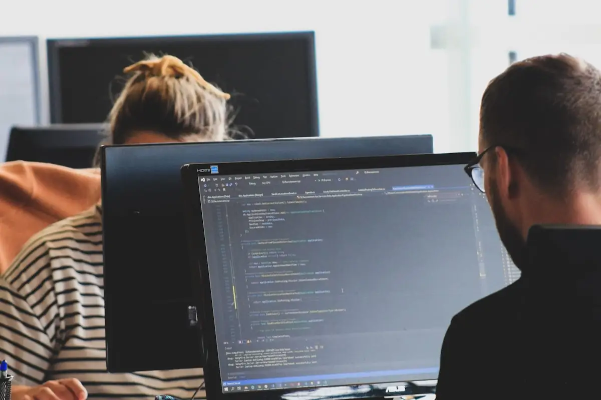Two engineers pairing at adjacent monitors