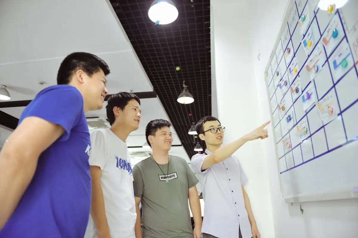 A team working through a problem at a whiteboard covered in notes